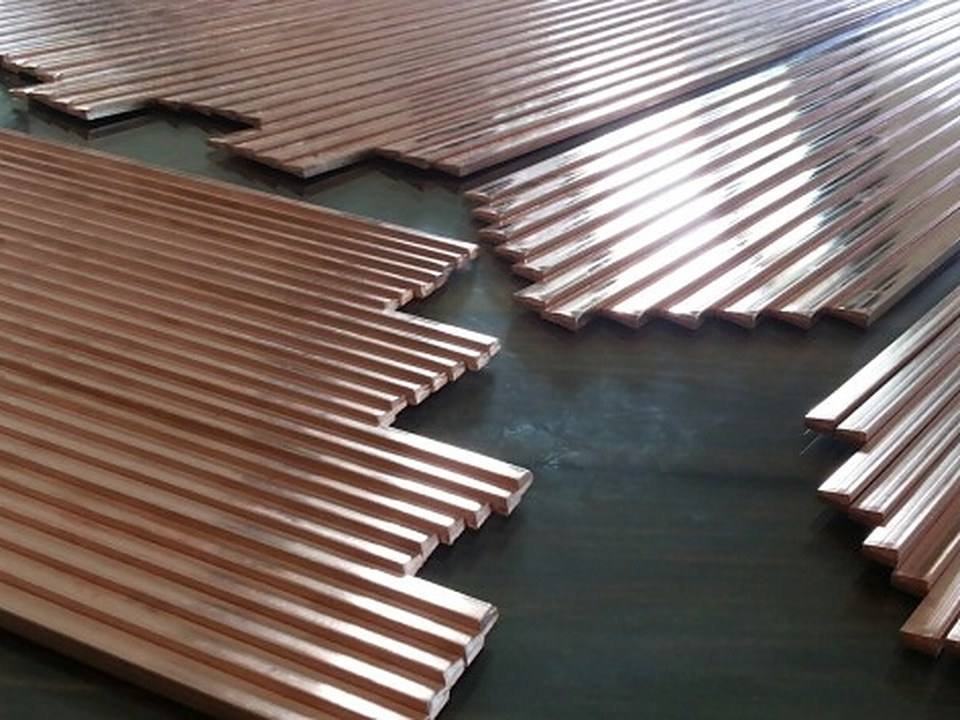 Rows of pentagon profile copper submersible sections on a workshop floor